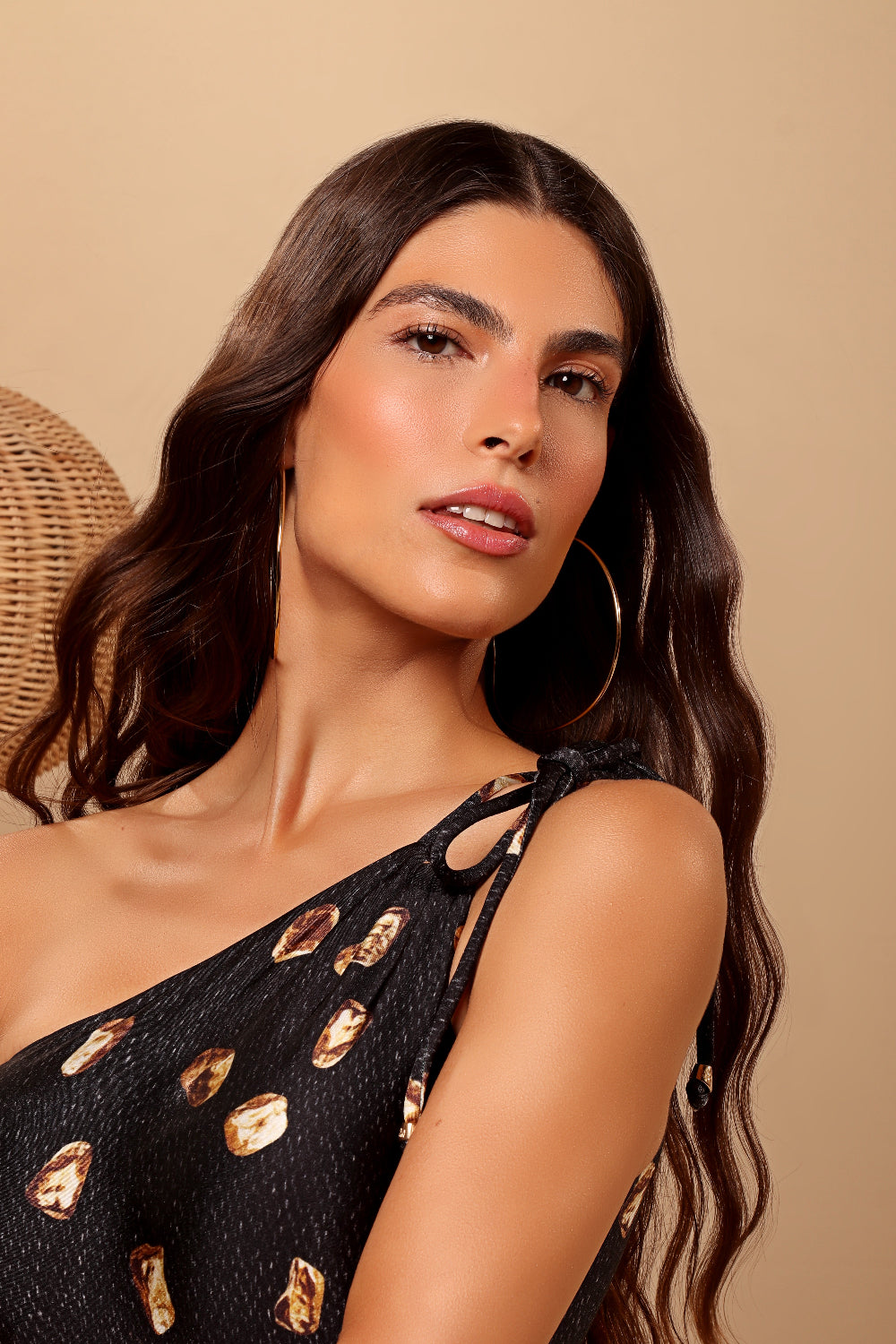 Woman wearing a black dress with gold accents against a beige background